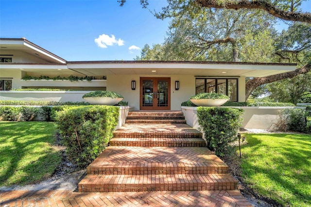 view of front facade with french doors, a front yard, and stucco siding