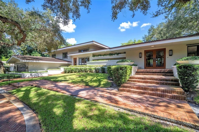 view of front facade featuring french doors, a front yard, and stucco siding