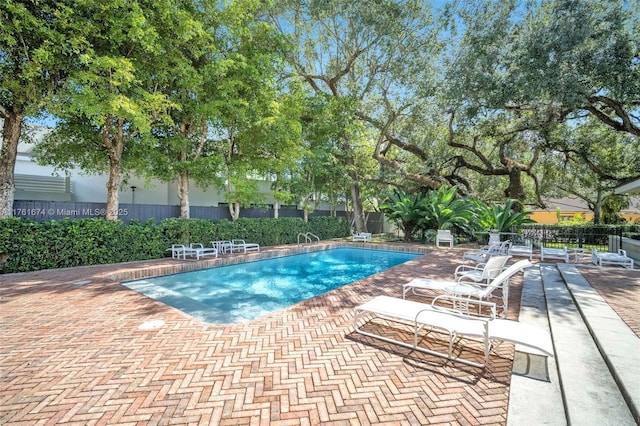 pool with a patio area and fence