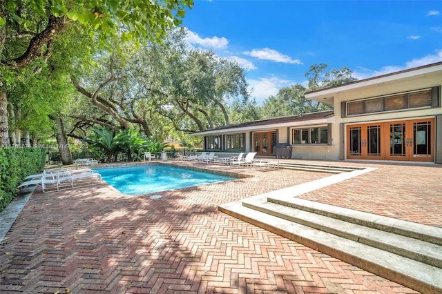 view of swimming pool featuring a patio, french doors, and a fenced in pool