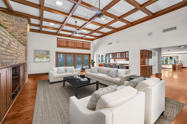 living room with visible vents, coffered ceiling, a towering ceiling, and wood finished floors