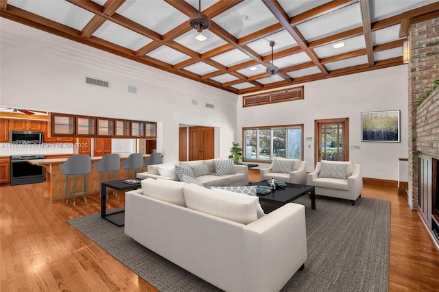 living room with light wood-style floors, visible vents, a ceiling fan, and a fireplace