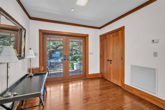 entryway with wood finished floors, baseboards, visible vents, ornamental molding, and french doors