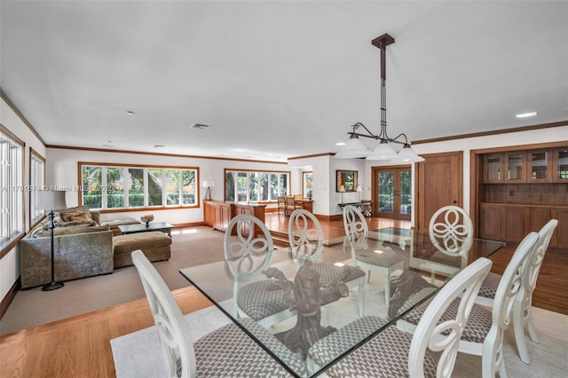 dining area featuring french doors, light wood-style flooring, baseboards, and crown molding