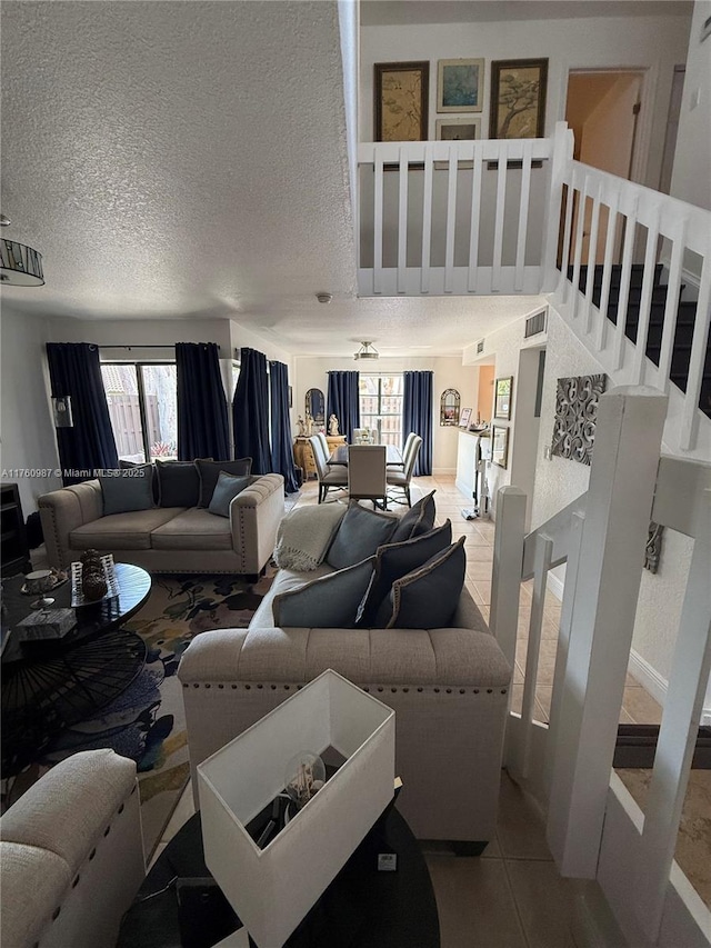 living area featuring tile patterned flooring, visible vents, a textured ceiling, and stairs