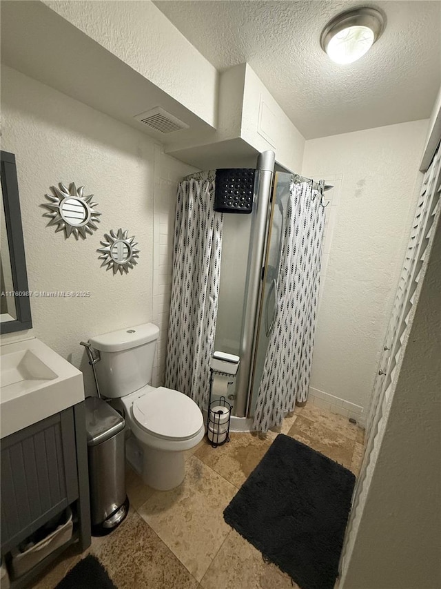 bathroom featuring a shower with curtain, visible vents, a textured ceiling, toilet, and a textured wall