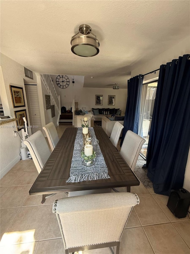 dining space with visible vents, a textured ceiling, stairway, light tile patterned floors, and baseboards