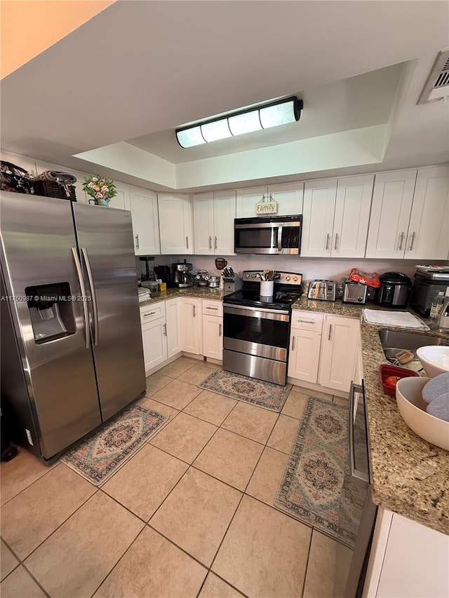 kitchen featuring a sink, a raised ceiling, appliances with stainless steel finishes, and light tile patterned floors