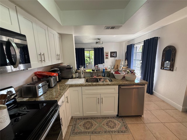 kitchen featuring a peninsula, white cabinets, plenty of natural light, and stainless steel appliances