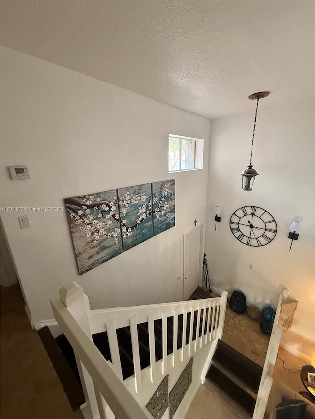 stairs featuring a textured ceiling and tile patterned flooring