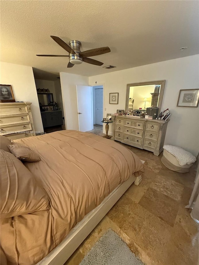 bedroom featuring ceiling fan, visible vents, and a textured ceiling