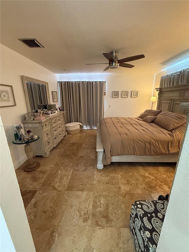 bedroom with ceiling fan, visible vents, and a textured ceiling