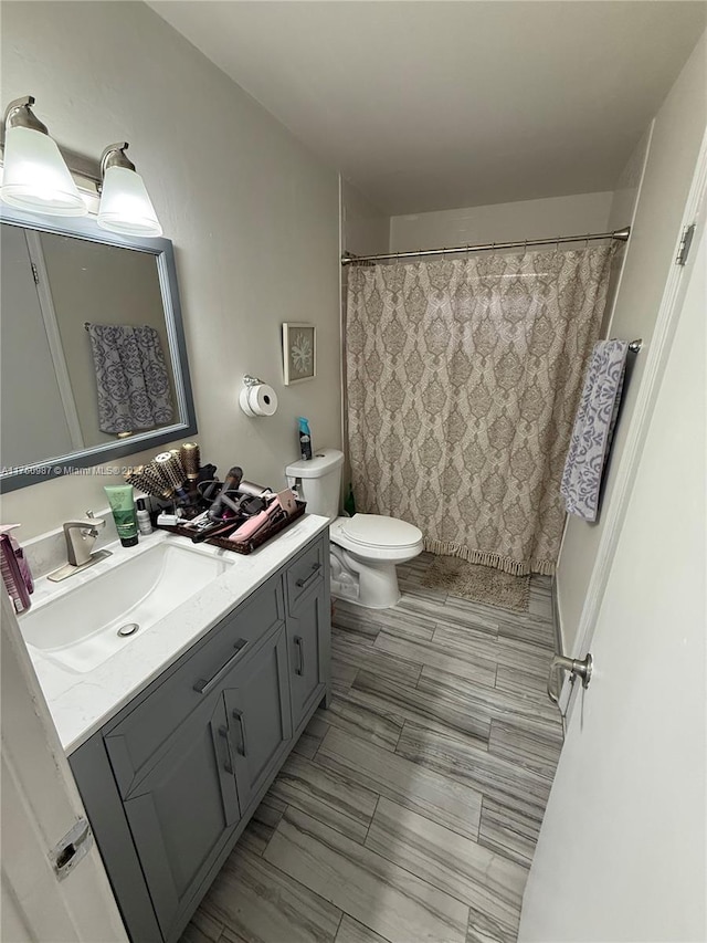 bathroom featuring toilet, vanity, and a shower with shower curtain