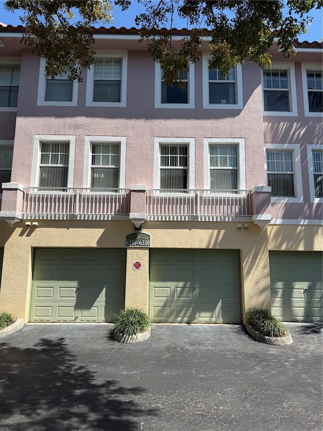 view of property with stucco siding, an attached garage, and driveway