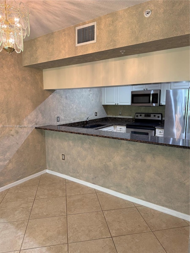 kitchen featuring visible vents, a sink, dark stone countertops, appliances with stainless steel finishes, and tile patterned flooring