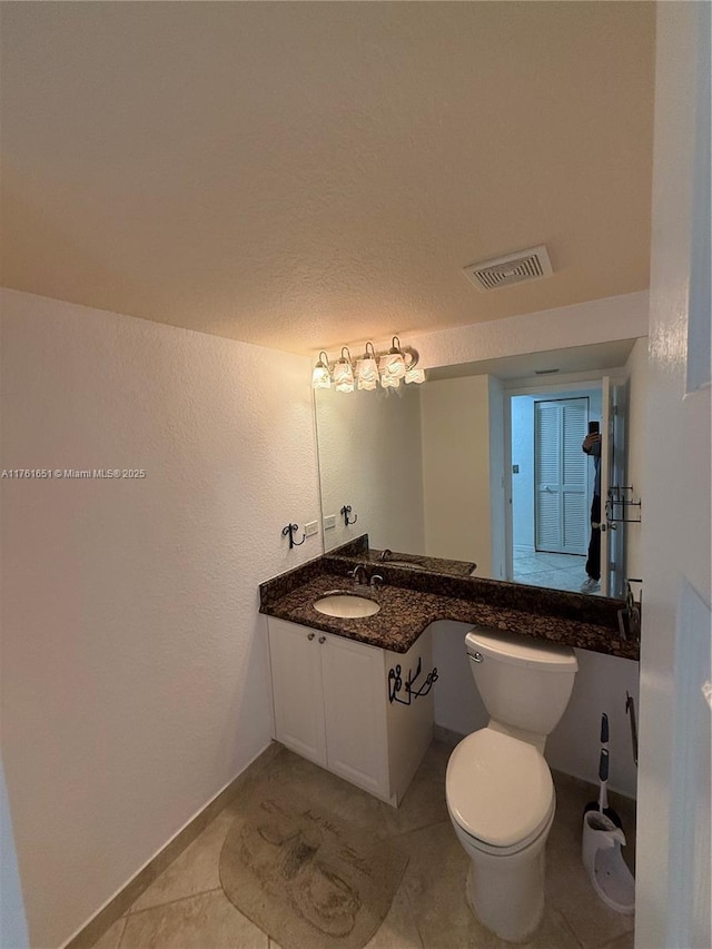 half bath featuring toilet, visible vents, tile patterned flooring, and vanity
