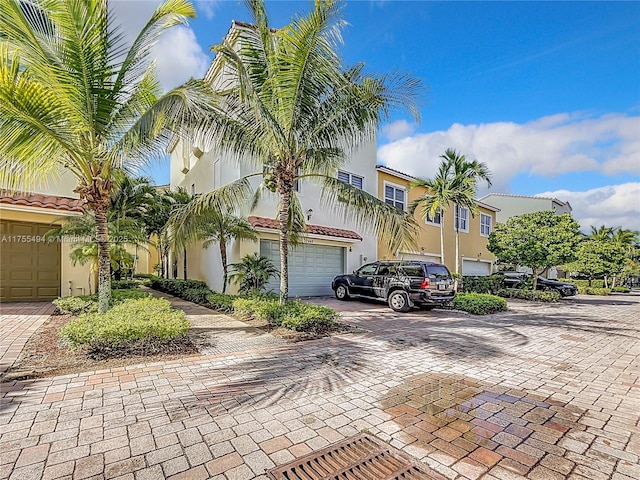 townhome / multi-family property with decorative driveway, a tile roof, and stucco siding