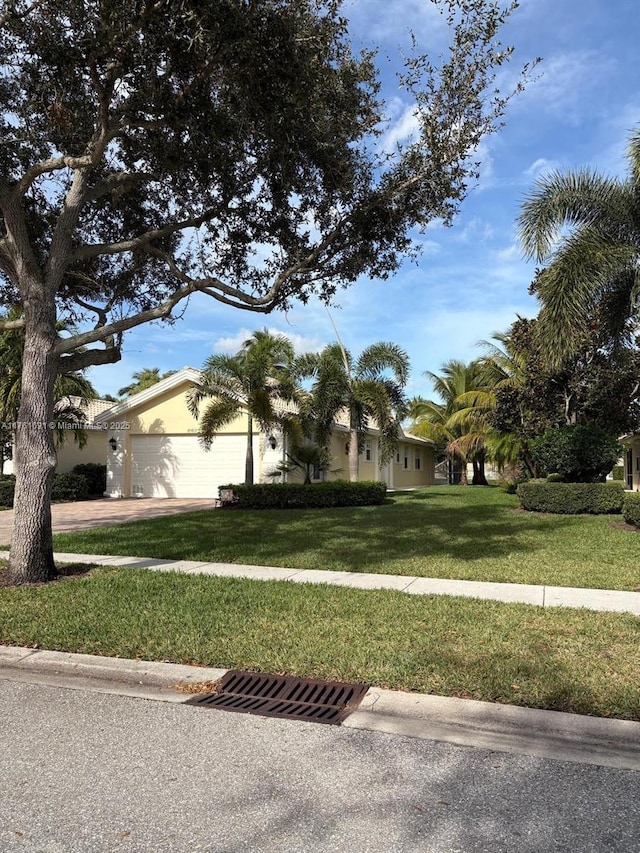 view of front of house featuring a front yard, an attached garage, driveway, and stucco siding