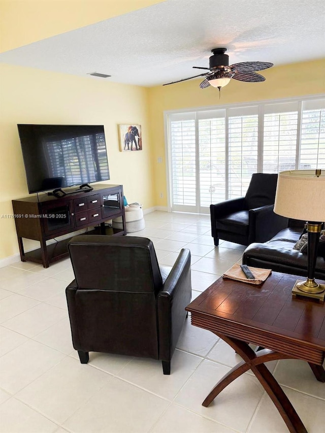 living room with visible vents, baseboards, light tile patterned floors, a textured ceiling, and a ceiling fan