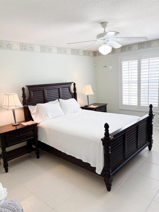 bedroom with light tile patterned floors, a ceiling fan, and a textured ceiling