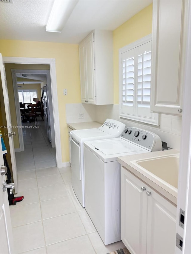 clothes washing area with light tile patterned floors, visible vents, cabinet space, a sink, and washing machine and dryer