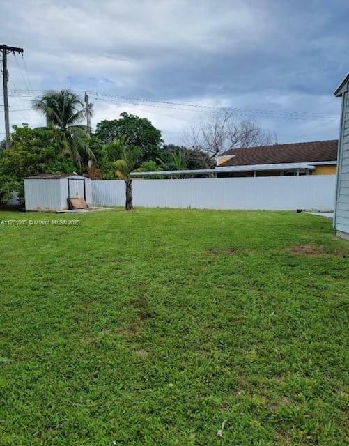 view of yard with a storage shed, an outdoor structure, and fence