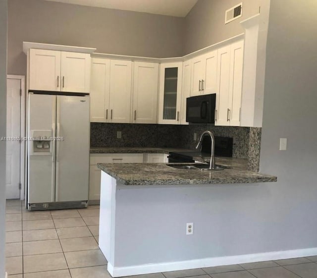 kitchen featuring light tile patterned floors, white cabinetry, black microwave, and white fridge with ice dispenser