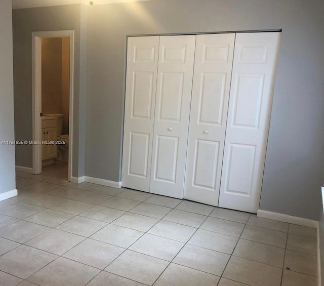 unfurnished bedroom with a closet, baseboards, and light tile patterned flooring