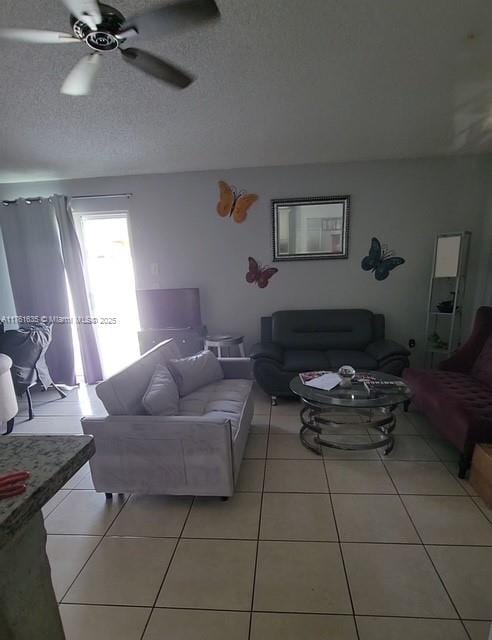 living room featuring light tile patterned floors, a textured ceiling, and ceiling fan