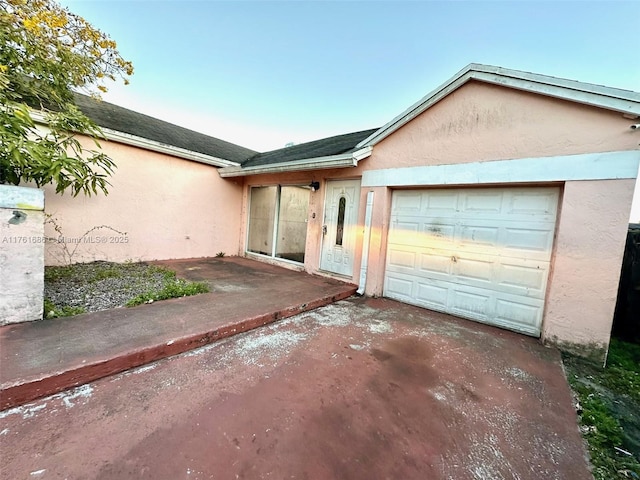 view of front of home with stucco siding, concrete driveway, a garage, and roof with shingles