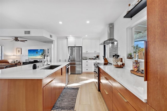 kitchen with visible vents, appliances with stainless steel finishes, light wood-style floors, wall chimney exhaust hood, and a sink