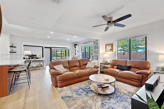 living room with visible vents, recessed lighting, light wood finished floors, a raised ceiling, and ceiling fan