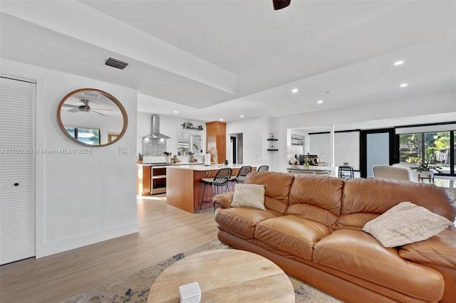 living area featuring visible vents, baseboards, recessed lighting, ceiling fan, and light wood-style floors