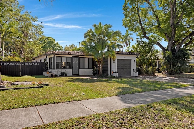 view of front of home featuring a front lawn, an attached garage, fence, and a sunroom