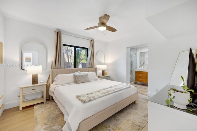 bedroom featuring connected bathroom, baseboards, light wood-style floors, and ceiling fan