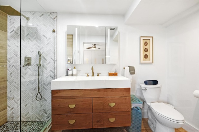 bathroom featuring a tile shower, toilet, vanity, and ceiling fan