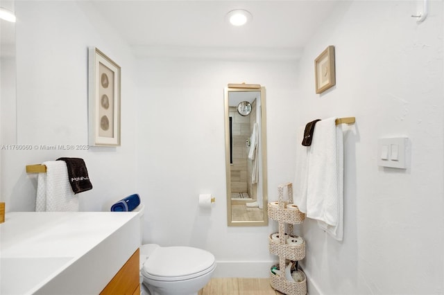 bathroom featuring toilet, vanity, and baseboards