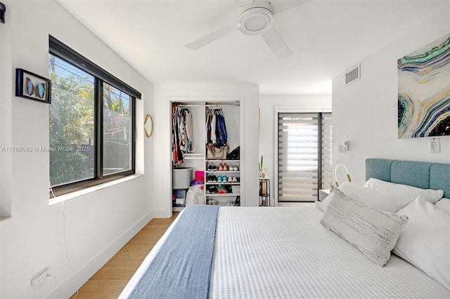 bedroom with visible vents, baseboards, ceiling fan, wood finished floors, and a closet