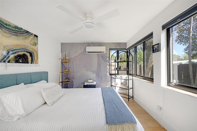 bedroom featuring ceiling fan, baseboards, wood finished floors, and a wall mounted AC