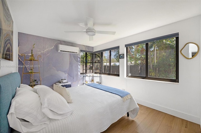 bedroom featuring wood finished floors, baseboards, a wall mounted air conditioner, and ceiling fan