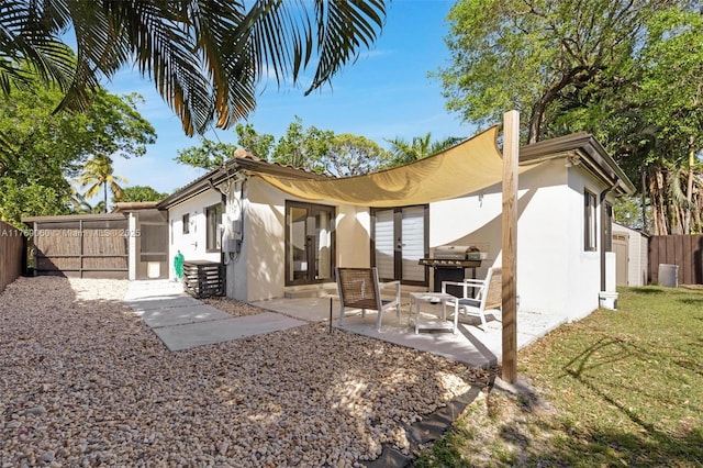 back of property with stucco siding, a fenced backyard, french doors, and a patio area