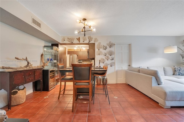 dining room featuring light tile patterned floors, visible vents, a textured ceiling, and a notable chandelier