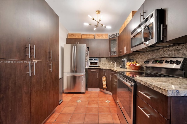 kitchen featuring dark brown cabinets, glass insert cabinets, light tile patterned floors, decorative backsplash, and appliances with stainless steel finishes