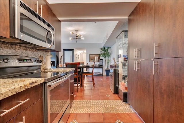 kitchen featuring light tile patterned floors, light countertops, appliances with stainless steel finishes, a notable chandelier, and tasteful backsplash