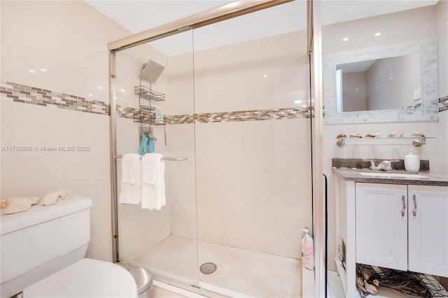 bathroom featuring a stall shower, toilet, tile walls, and vanity