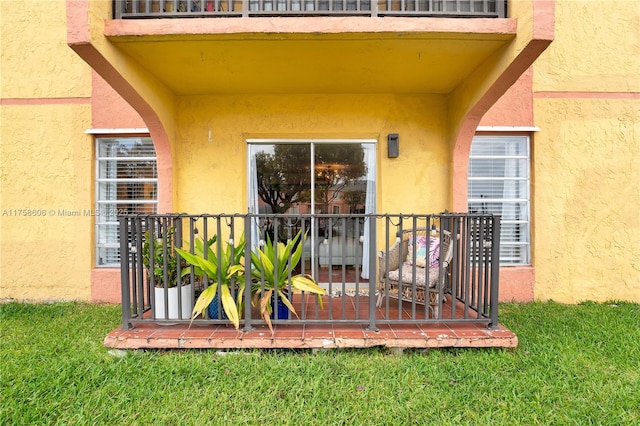 view of exterior entry with a lawn and stucco siding