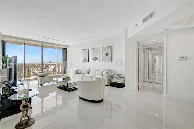 living area with rail lighting, visible vents, and floor to ceiling windows