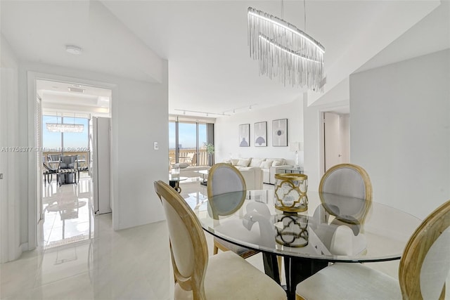 dining area featuring light tile patterned floors, a notable chandelier, floor to ceiling windows, and rail lighting