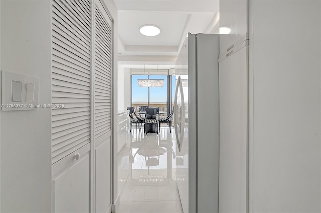 hallway with a chandelier and light tile patterned flooring