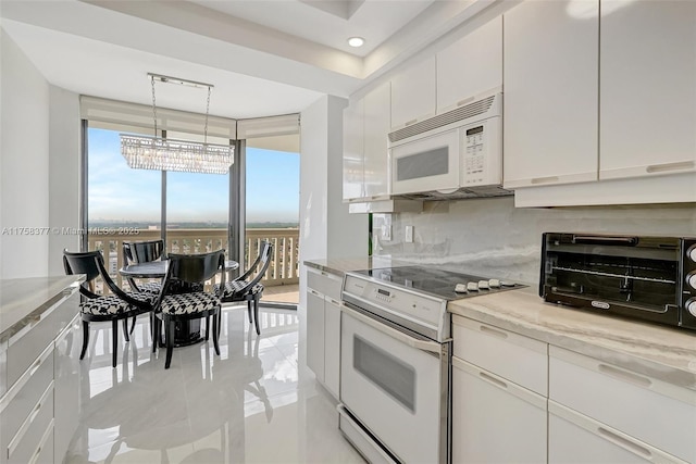 kitchen with white appliances, a toaster, backsplash, white cabinets, and a wealth of natural light